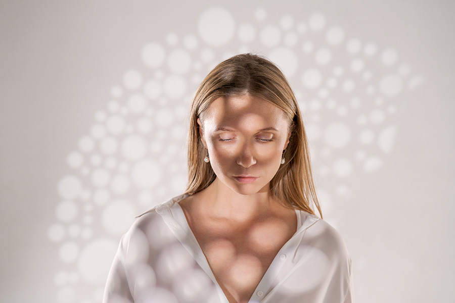 sweet woman posing on light background with light shadows in translucent shirt